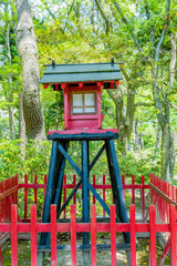 Small wooden replica of shinto shrine in Japanese garden park.