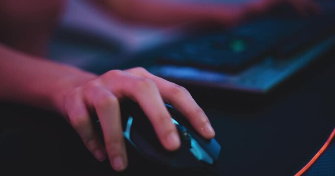 Footage close-up mouse of Young Asian esport women gamers playing online video games on the computer with neon light at home. Girl gaming player feels enjoy technology broadcast live streaming.