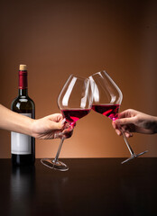 Scene of two people celebrating with red wine glasses, tall glasses colliding, cooperation and...