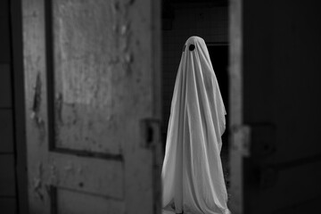 Ghost in a white sheet walking in an abandoned old house at night