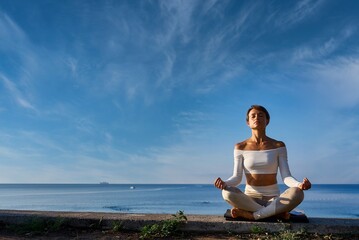 Young fitness woman practicing yoga on the beach, healthy lifestyle concept