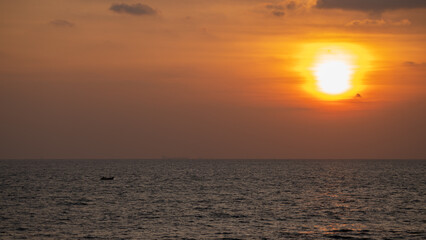 Sunset on the horizon, a small fishing boat traveling alone.