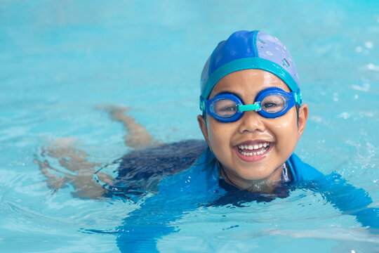 Little girl learning and enjoying to swim in indoor pool.