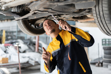 Caucasian man mechanic checking suspension system at car service