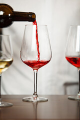 Vertical closeup shot of glass with wine pouring by sommelier