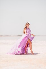 Fototapeta na wymiar Woman pink salt lake. Against the backdrop of a pink salt lake, a woman in a long pink dress takes a leisurely stroll along the white, salty shore, capturing a wanderlust moment.