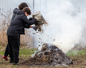 Burning dry grass in the spring garden. A man cleans the grass from fire