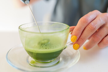 Girl brews matcha green tea in a transparent cup