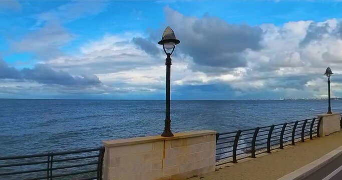 Cammino in auto sul lungomare con cielo nuvoloso e vista a 360&deg;