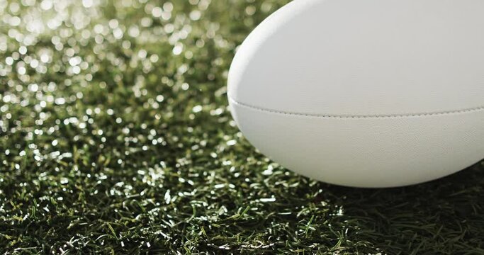White rugby ball on sunlit grass with copy space, slow motion