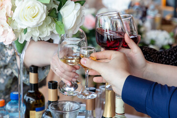 Hands of people clinking glasses with red and white wine in restaurant