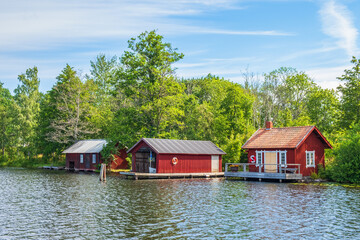 Fototapeta na wymiar Beach with a red cabin and boathouse on the Göta Canal in Sweden