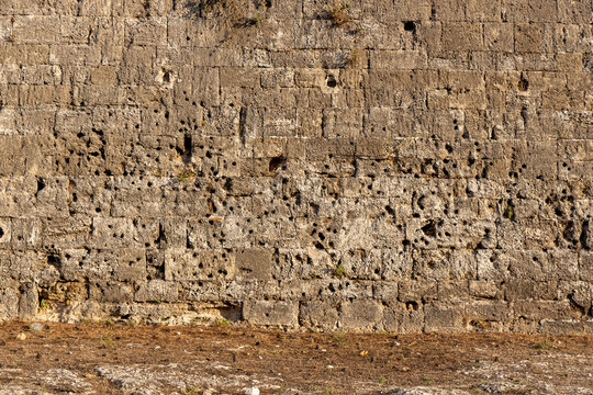 War damage, bullet holes in stone wall in the moat of old town Rhodes, Geece