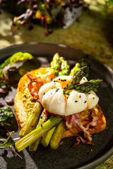 Grilled Toast witch Asparagus, avocado, Poached egg, greens, bacon on green textured background. banner, menu recipe place for text, top view. Traditional breakfast.