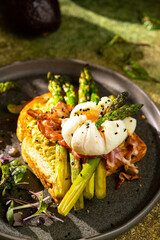 Grilled Toast witch Asparagus, avocado, Poached egg, greens, bacon on green textured background. banner, menu recipe place for text, top view. Traditional breakfast.
