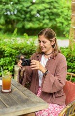 Cute russian woman taking a photo of ice tea in summer garden