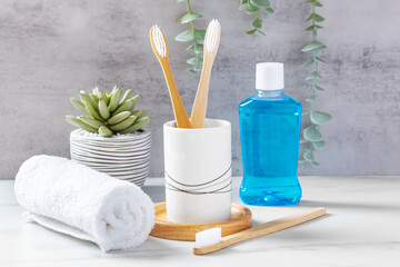 Dental health care and oral hygiene concept, bamboo toothbrushes in cup with mouthwash and towel - obrazy, fototapety, plakaty