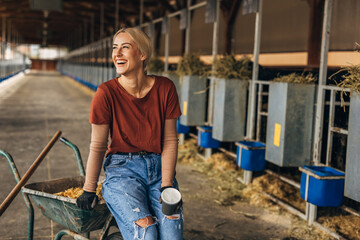 Beautiful farm girl sitting on a cart in a stable.