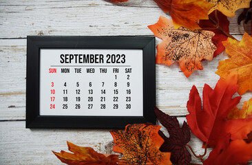 September 2023 monthly calendar with maple leaf on wooden background