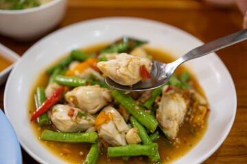 The spoon was scooping up fried crabmeat with yellow pepper and long bean from the plate.