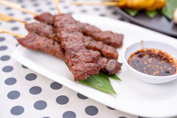 Skewered grilled beef served in a white plate with Thai Spicy Sauce.