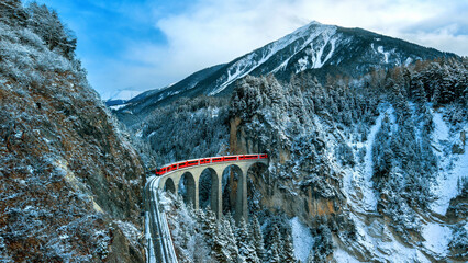 Landscape of Train passing through famous mountain in Filisur, Switzerland. Landwasser Viaduct world heritage with train express in Swiss Alps snow winter scenery.