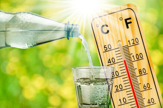 thermometer shows high temperature in summer heat and bottle with water with drinking glass
