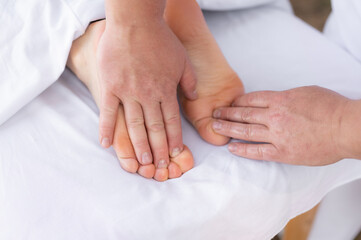Close-up of man doing foot massage on white background. Reflexology foot massage. Tired feet concept