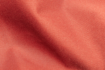 Red velvety synthetic fabric with folds as a texture, background, pattern