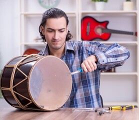 Young handsome repairman repairing drum