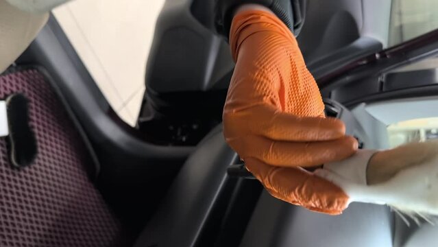 Detailing center employee in rubber gloves applies foam to the brush for cleaning the dashboard in the car interior. Vertical video. Concept: Auto Car Service, Car Wash. High quality FullHD footage