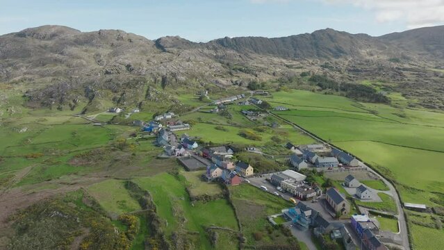 Drone establishing shot flying over colourful Allihies village to the remains of an old Coppermine workings in the mountains of West Cork Ireland on a sunny spring day