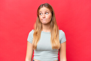 Young beautiful woman isolated on red background making doubts gesture looking side