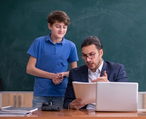 Young male teacher and schoolboy in the classroom