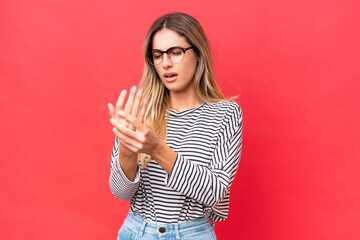 Young Uruguayan woman isolated on red background suffering from pain in hands