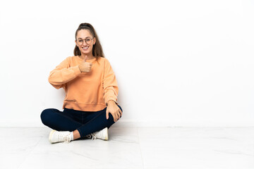 Young woman sitting on the floor giving a thumbs up gesture