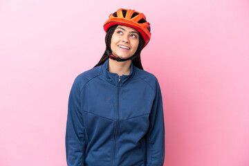 Teenager cyclist girl isolated on pink background thinking an idea while looking up
