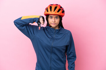 Teenager cyclist girl isolated on pink background showing thumb down with negative expression