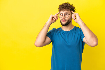 Fototapeta na wymiar Young handsome caucasian man isolated on yellow background having doubts and thinking
