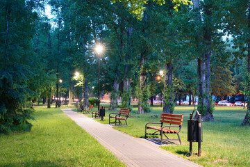 Park nocą z rozświetlonymi latarniami i ławeczkami © Mariusz