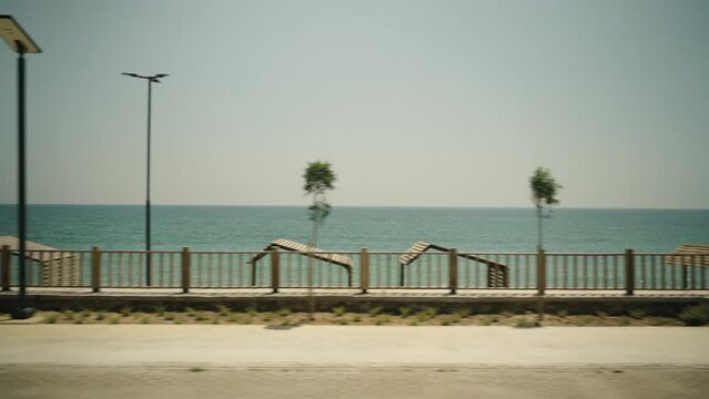 Beach huts by the sea, view from a car moving along the road.