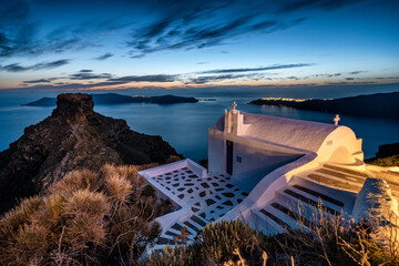 Blue hour at small white chapel overlooking the sea and islands on the Greek island of Santorini