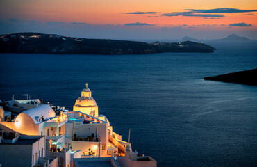 Blue hour in Fira overlooking an illuminated chapel and caldera on Greek island of Santorini - obrazy, fototapety, plakaty