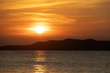 Intense orange and pink sunset above the water in Duli Beach, Palawan, Philippines. Sun going down, burning sky, golden hour.