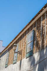 Fototapeta na wymiar Facade of old house under construction, half whitewashed, in the city of La Laguna. Green wooden windows. Sunny day. Colorful houses Tenerife, Canary Islands, Spain.