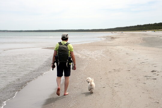 Person, Mensch mit kleinem weißen Hund, Wandern am Sandstrand der Ostsee, Rügen, Schaabe, Nehrung, Deutschland