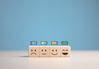 Percent of battery level from sadness to smiley face on wooden cube. Energy to motivate life, Emotional happiness level, World mental health day. Satisfaction, Burnout state, and Positive Thinking.