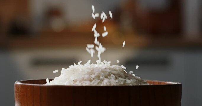 Rice fall into raw wooden cup side view home kitchen blurred background Sushi sashimi, Japanese Asian Ethnicity cookery. Wooden rice bowl, healthy clean eating. Grain seed vegan uncooked white rice