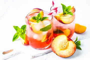 Peach cocktail, iced peach tea, fruit drink with fresh fruits and mint.