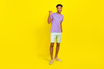 Fototapeta na wymiar Full body photo of young guy direct finger empty space wear summer stylish trendy garment brand store isolated on yellow color background